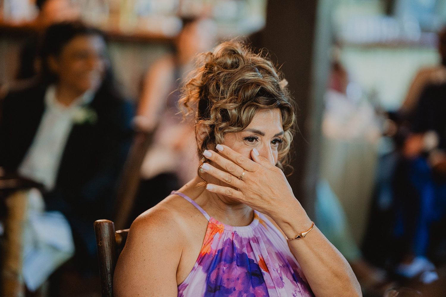 Guest in purple dress shows emotional reaction during wedding reception speech.