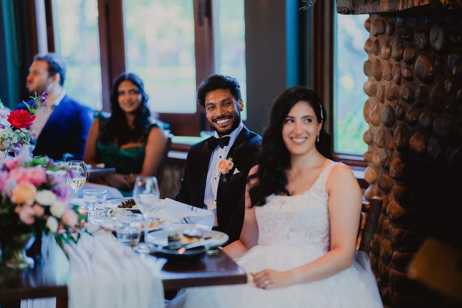 Wedding reception table settings with colorful floral centerpieces and elegant place settings in rustic venue.