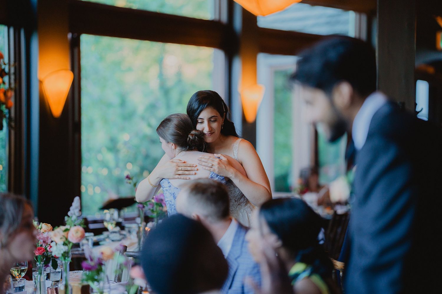Wedding reception venue with ambient lighting and large windows overlooking natural scenery.