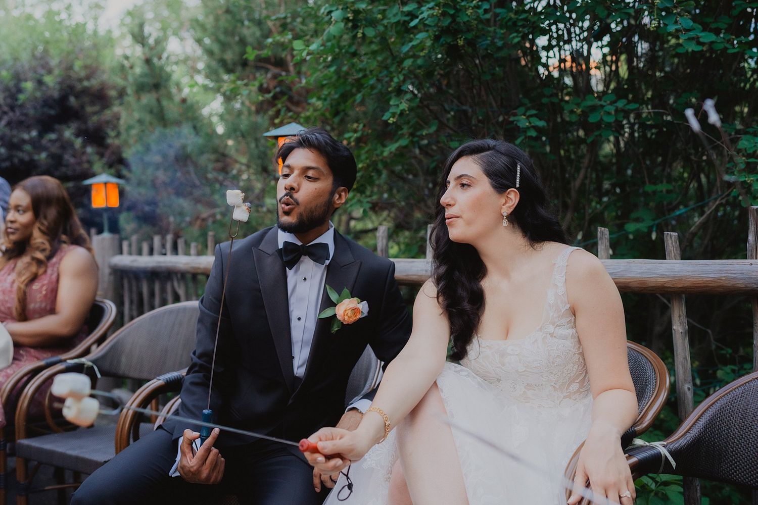 A couple in wedding attire shares a joyful moment while sitting together at their outdoor celebration.