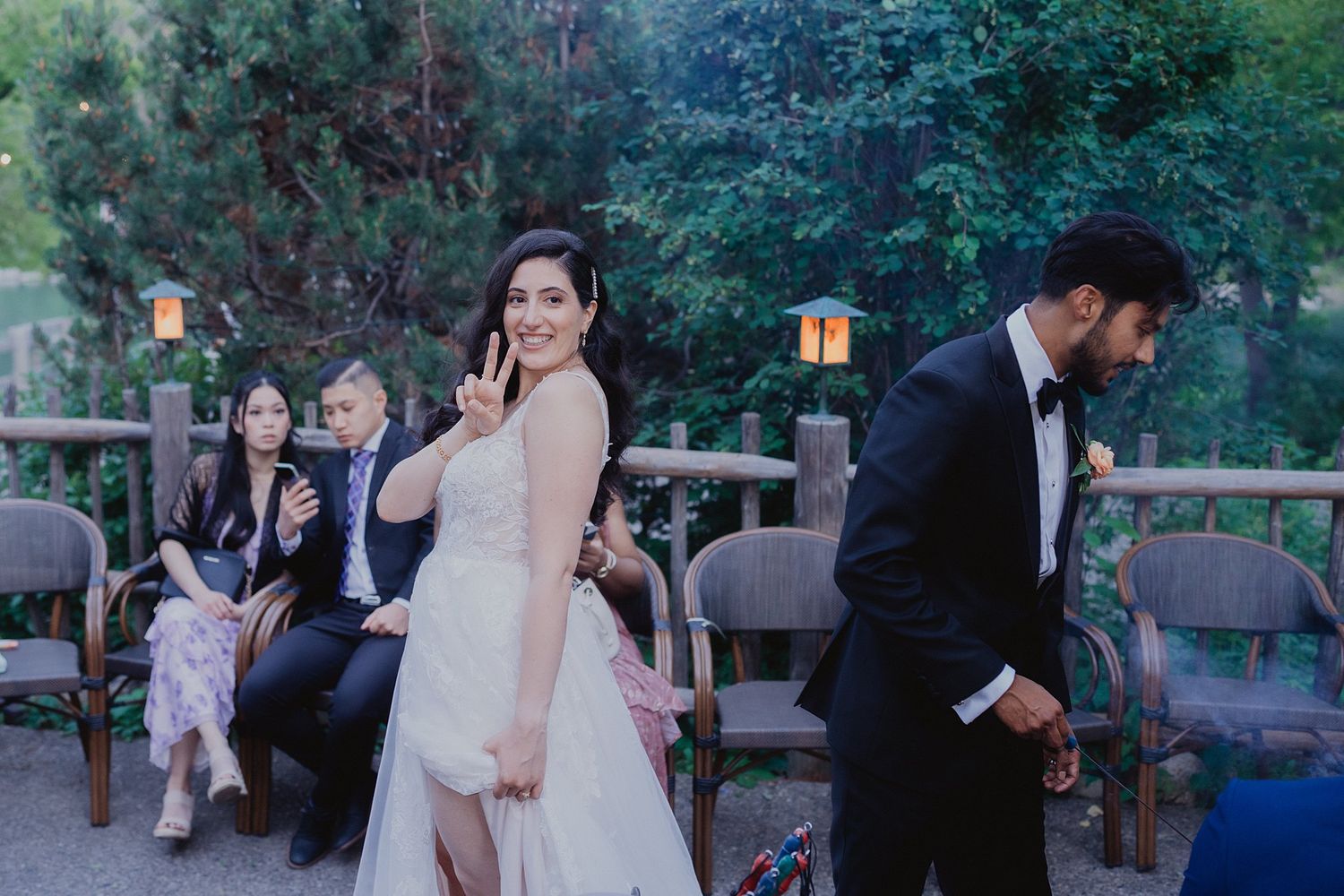Guests gather outdoors at dusk for an elegant wedding celebration in a garden setting.