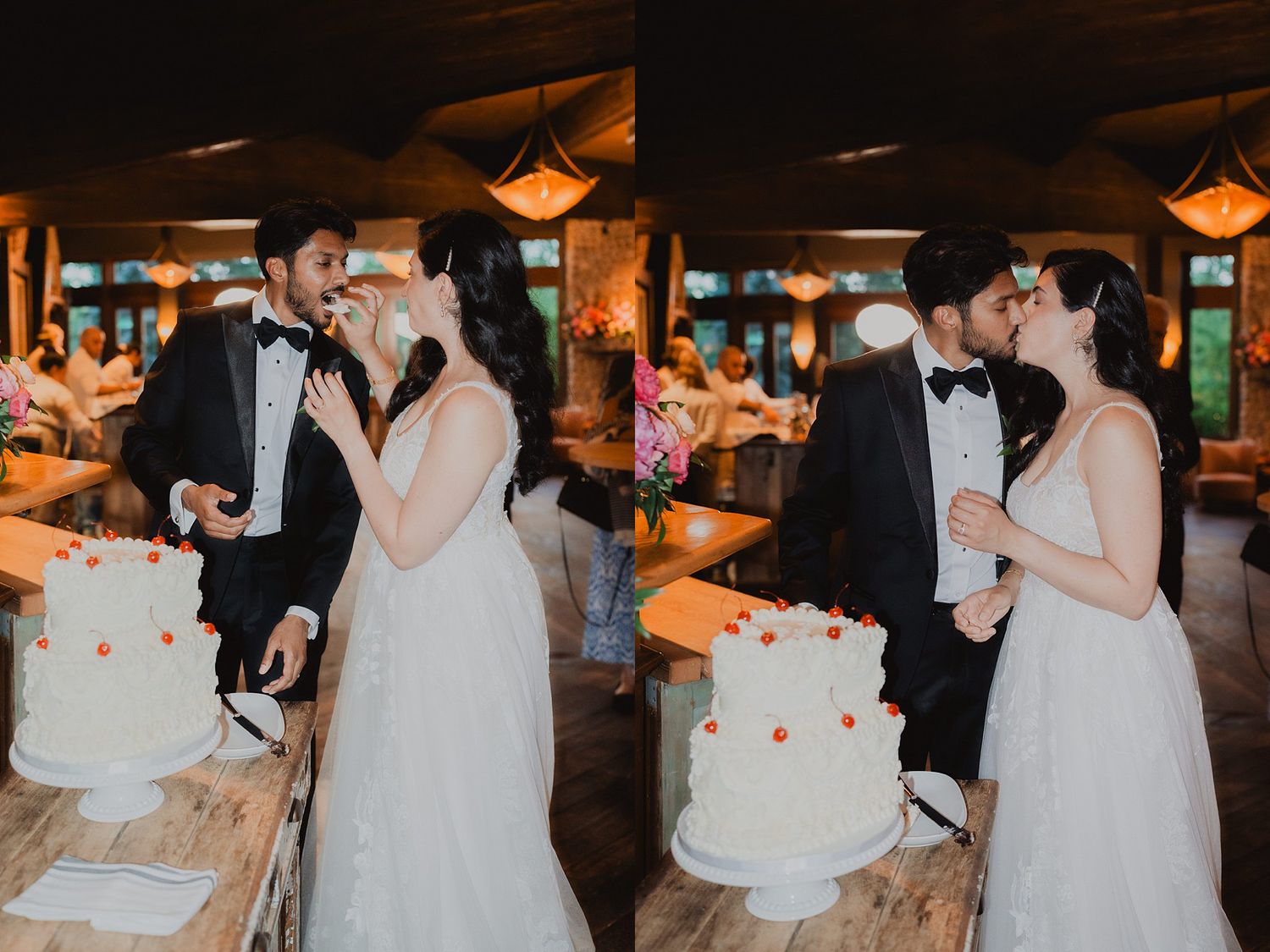 Wedding reception celebration with guests gathered around a white tiered cake in a rustic venue.