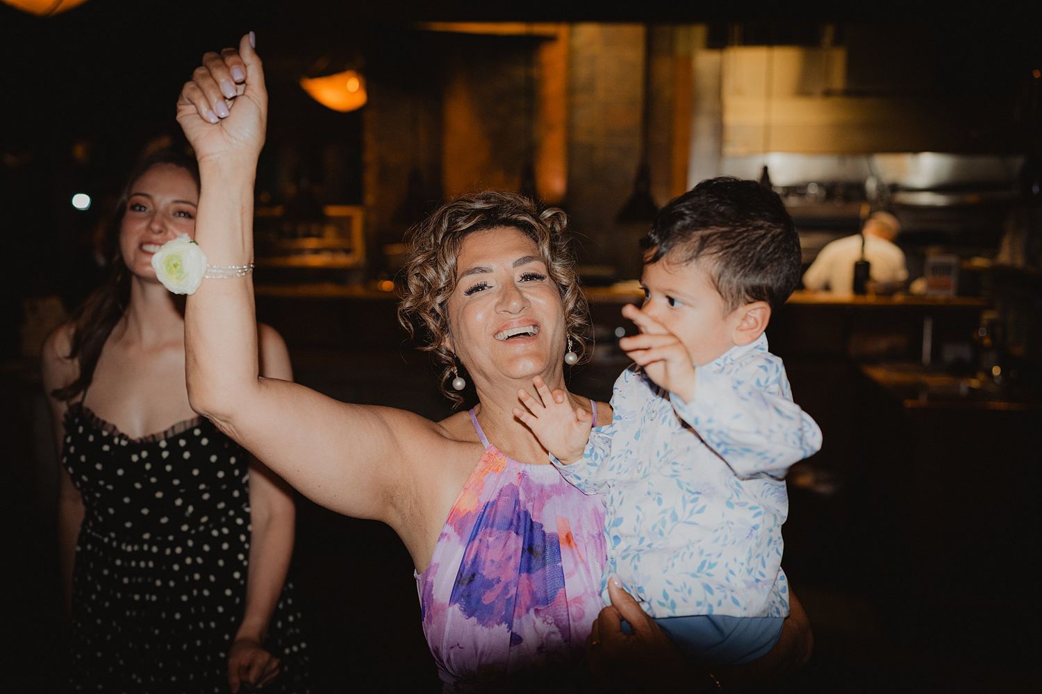 Joyful dancing scene at a wedding reception with warm ambient lighting.