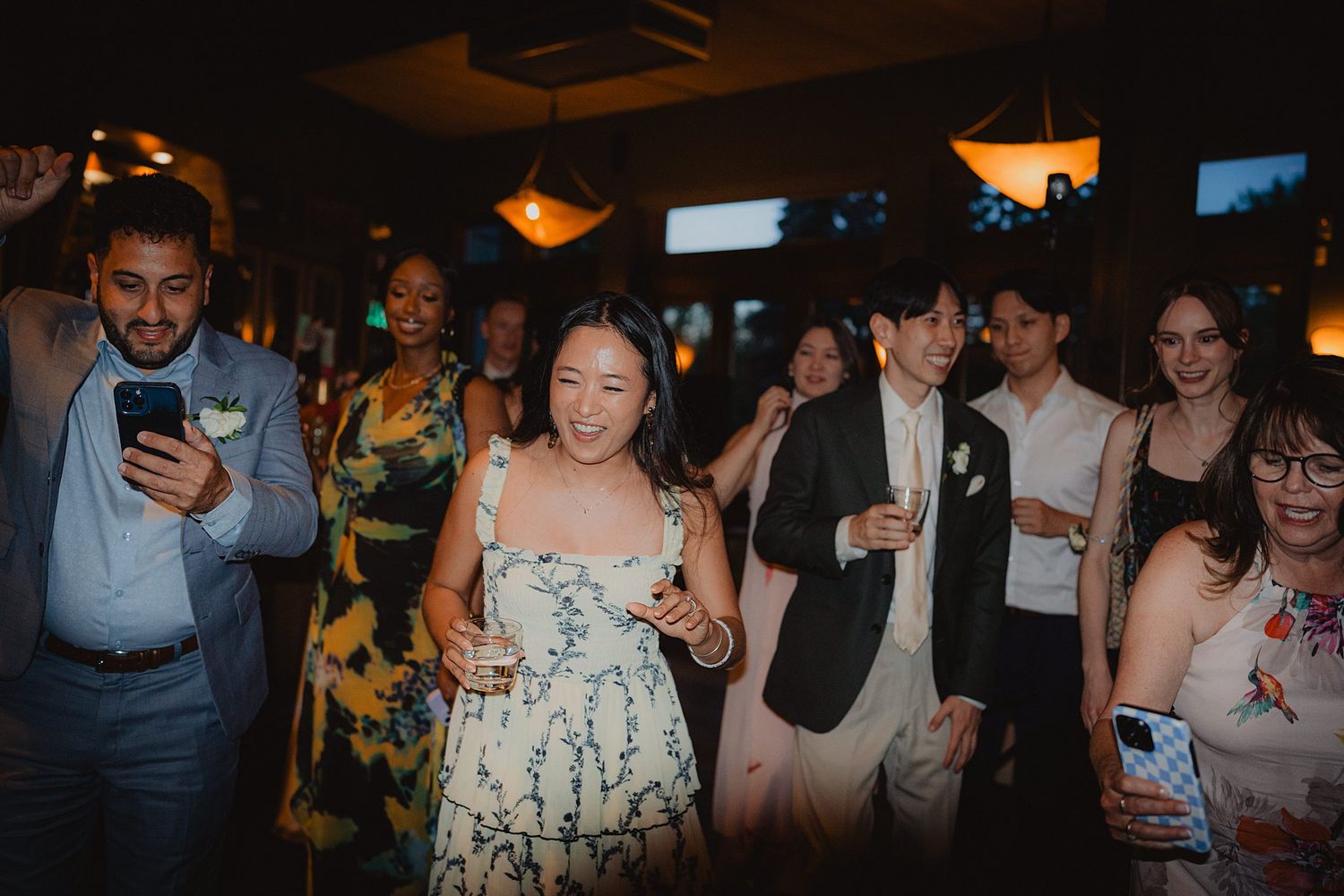 People dancing and celebrating at a dimly lit party venue with festive lighting and decorations.