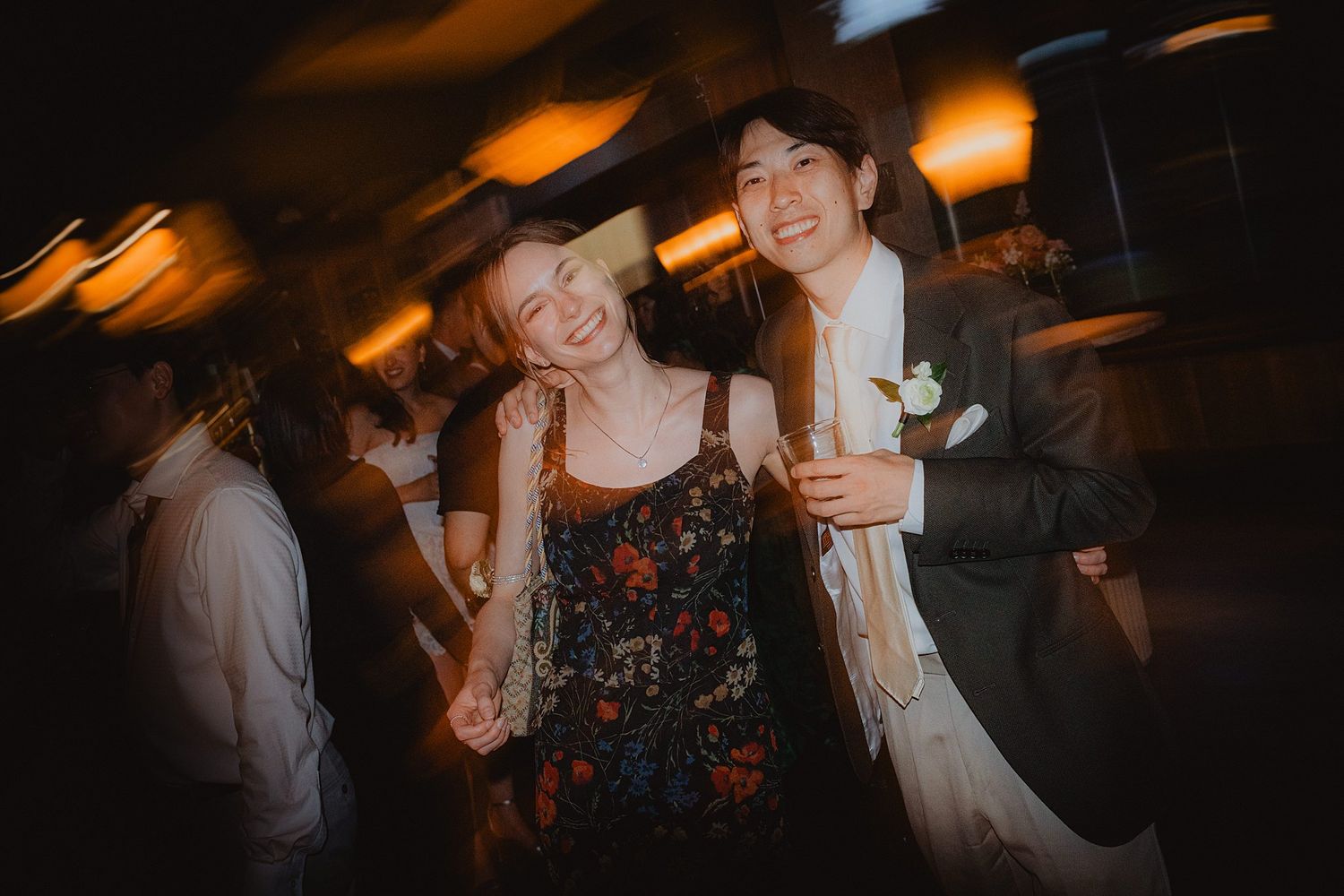 Wedding reception dance floor filled with guests celebrating under warm ambient lighting.