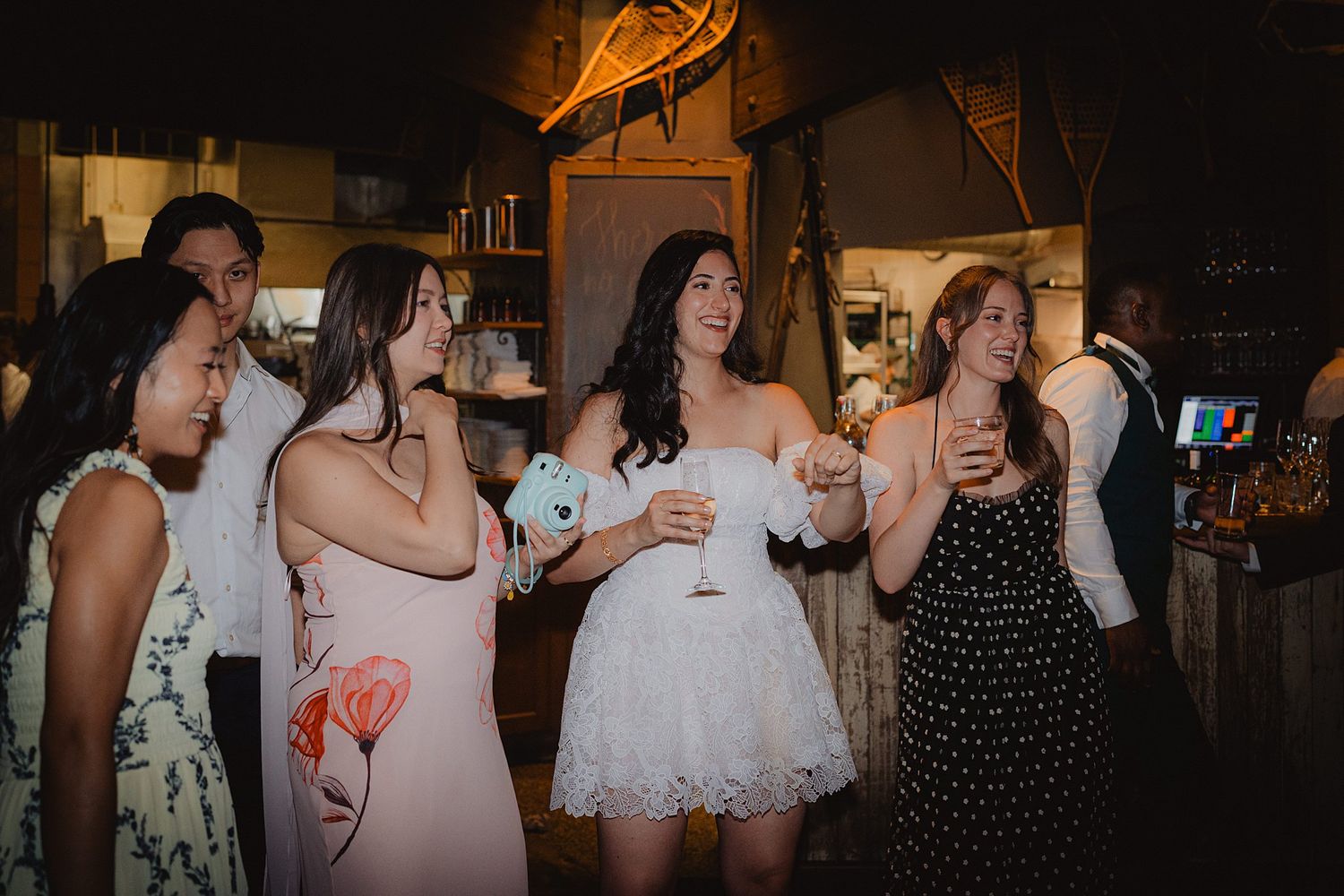 Group of wedding guests enjoying drinks and festivities at an evening reception.
