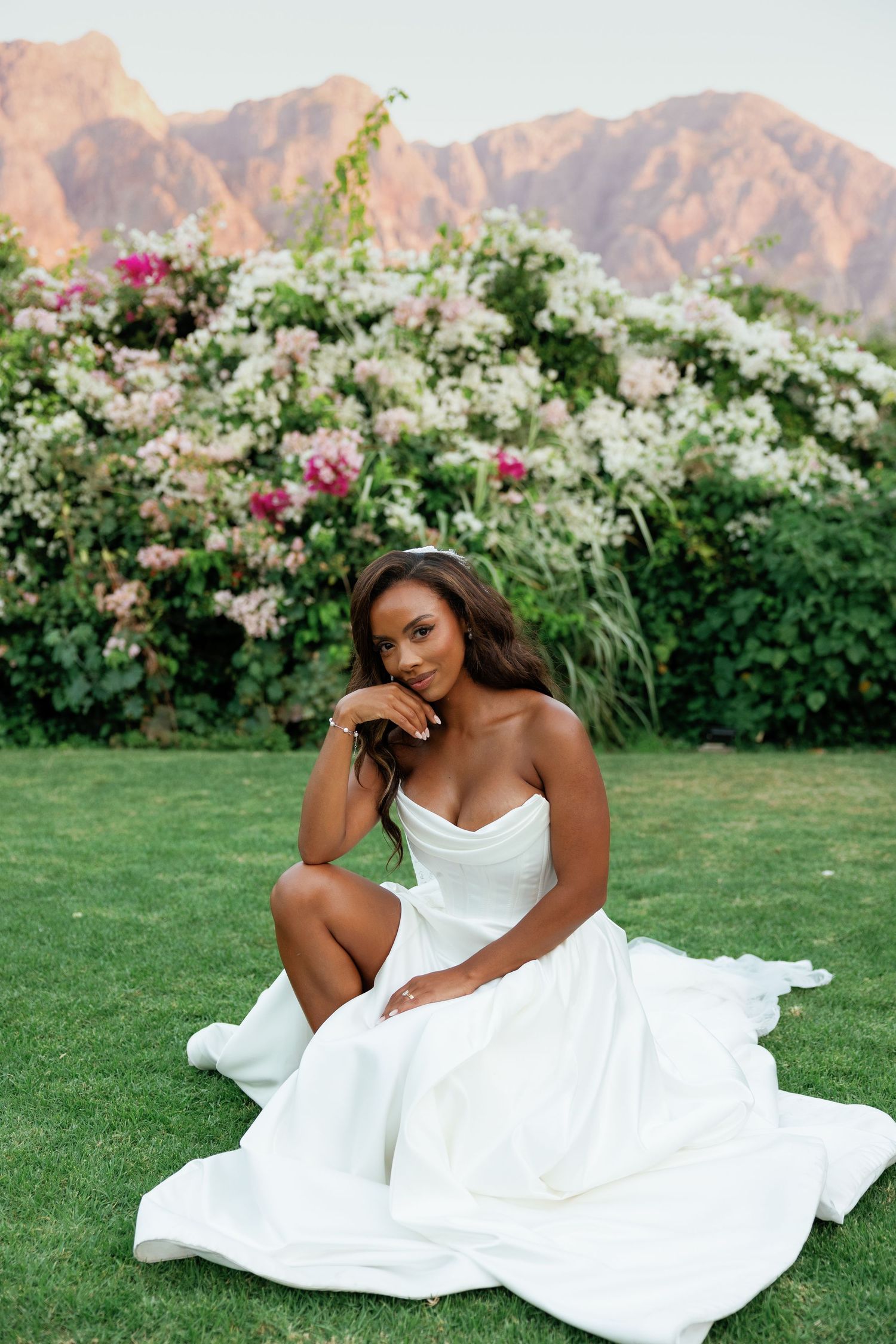 A stunning bridal portrait against mountain scenery with white and pink floral landscaping.