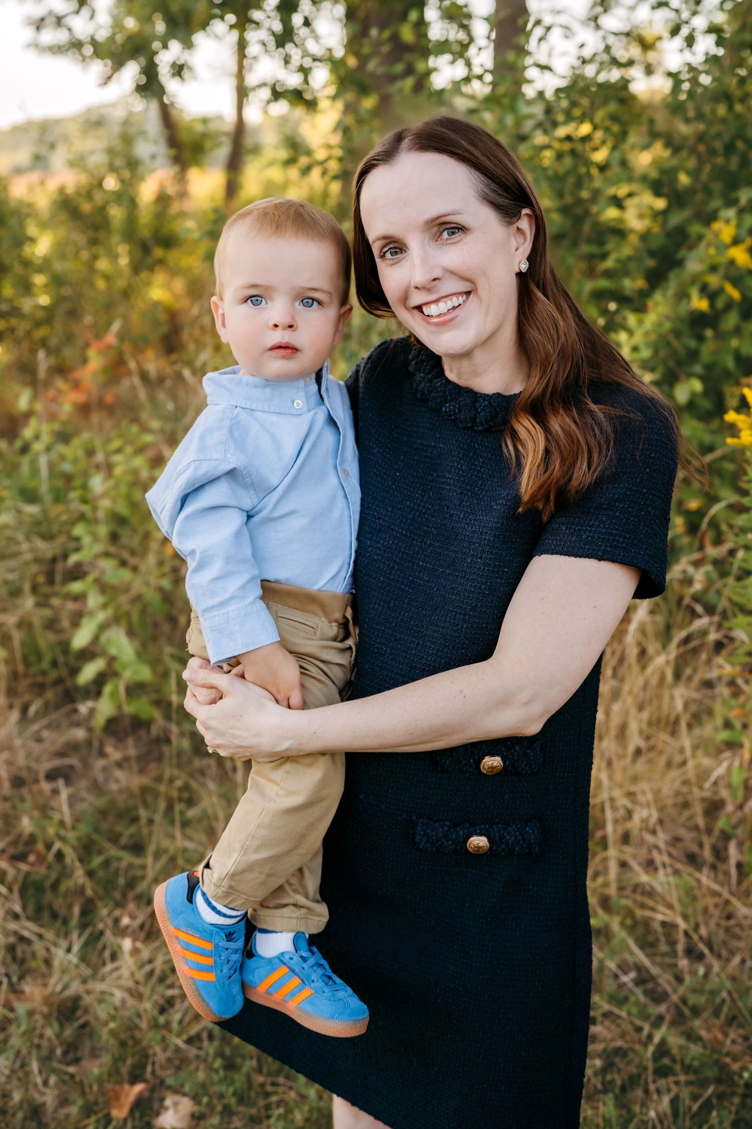 A casual outdoor family portrait session with navy and light blue outfits against a natural backdrop.