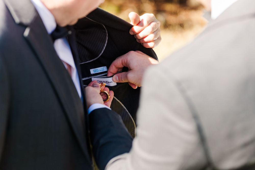 A person in a black suit adjusts their tie while getting dressed for a formal occasion.