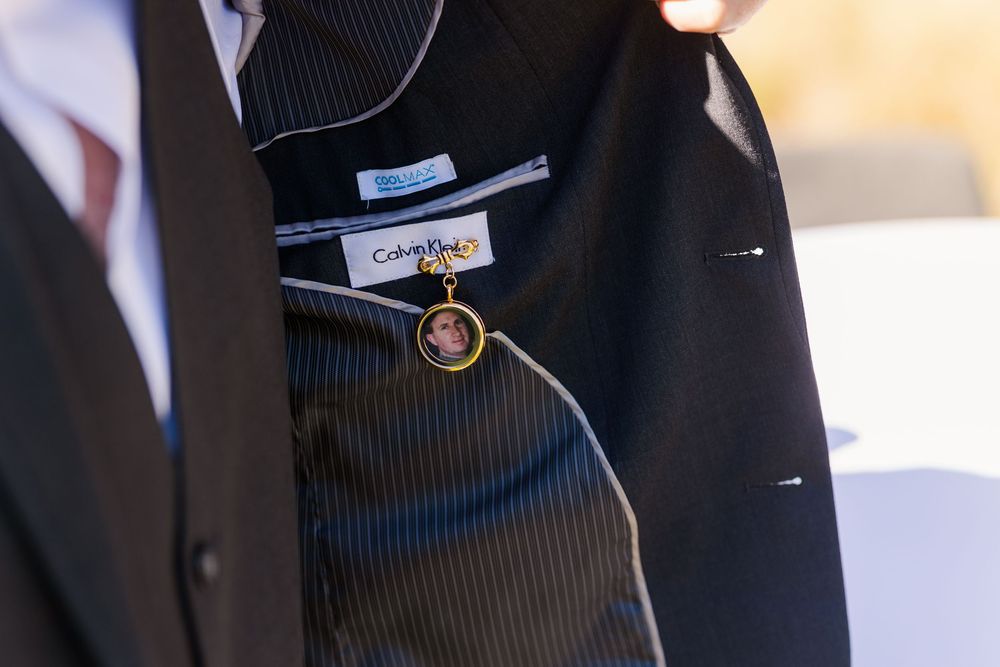 Professional wearing a dark pinstripe suit with a blue tie stands against a blurred background.