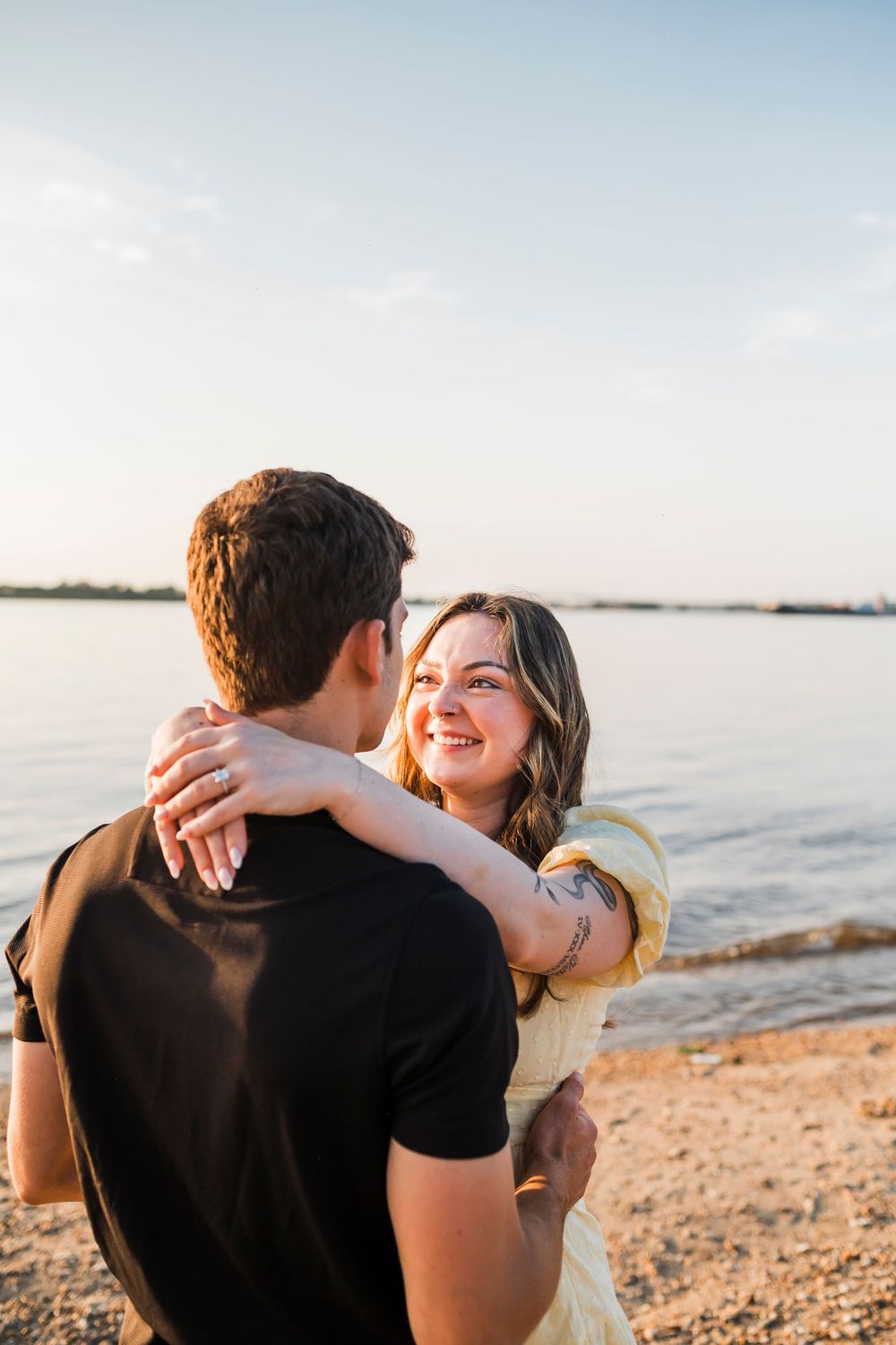 A romantic embrace captured during sunset at a waterfront location.