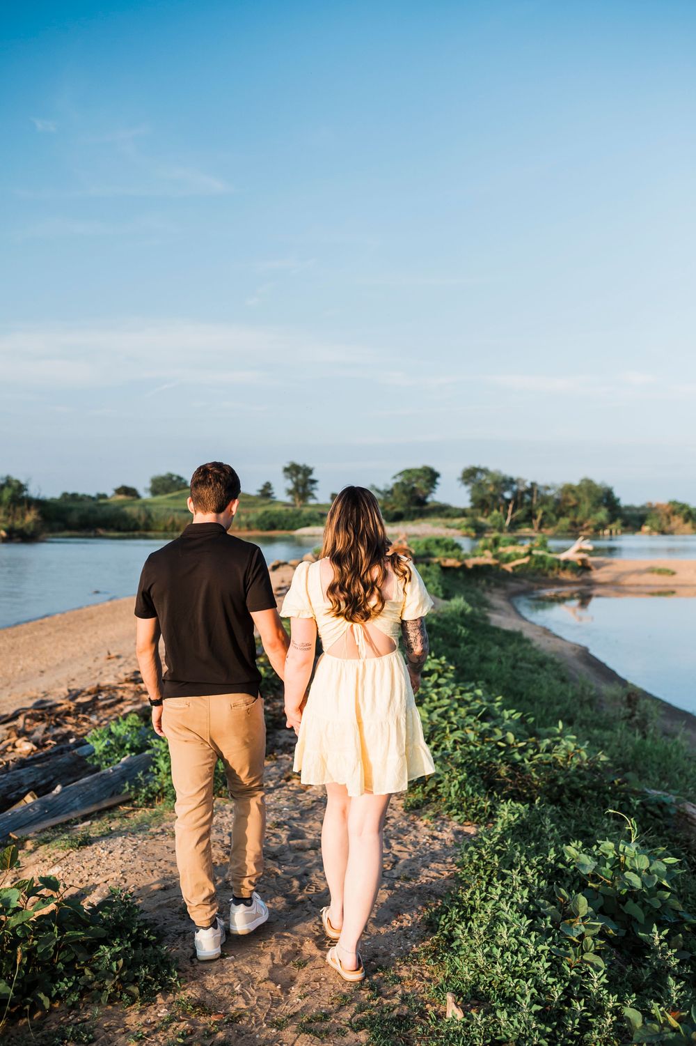 Couple walking together on a scenic coastal path during golden hour with water views.