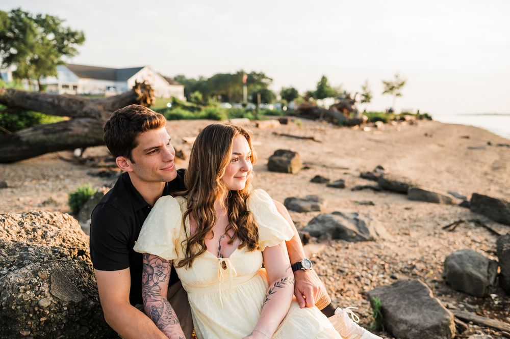 Couple sharing an intimate moment together on rocky coastal terrain at sunset.