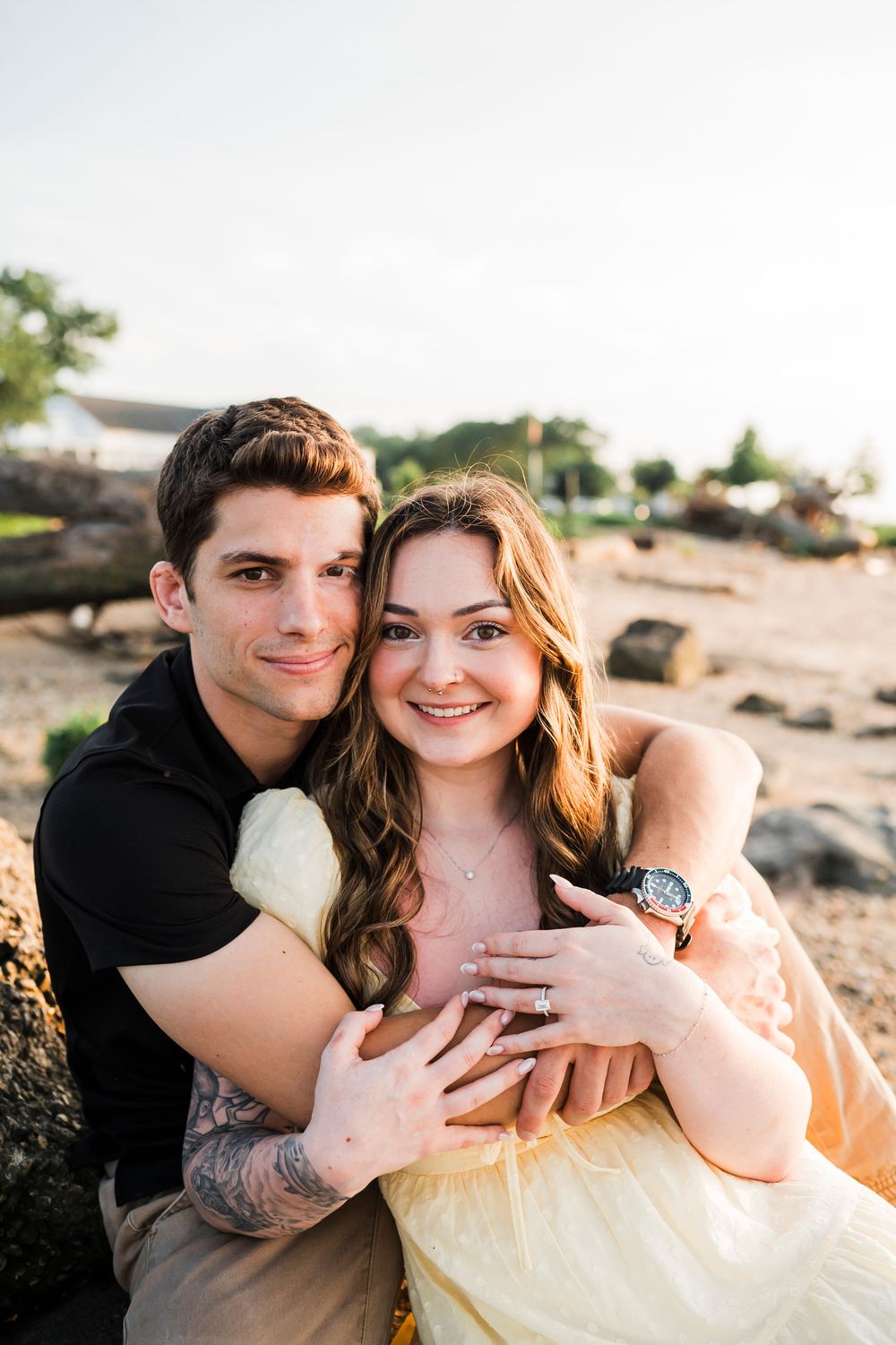 A couple shares intimate moments on a rocky shoreline during sunset.