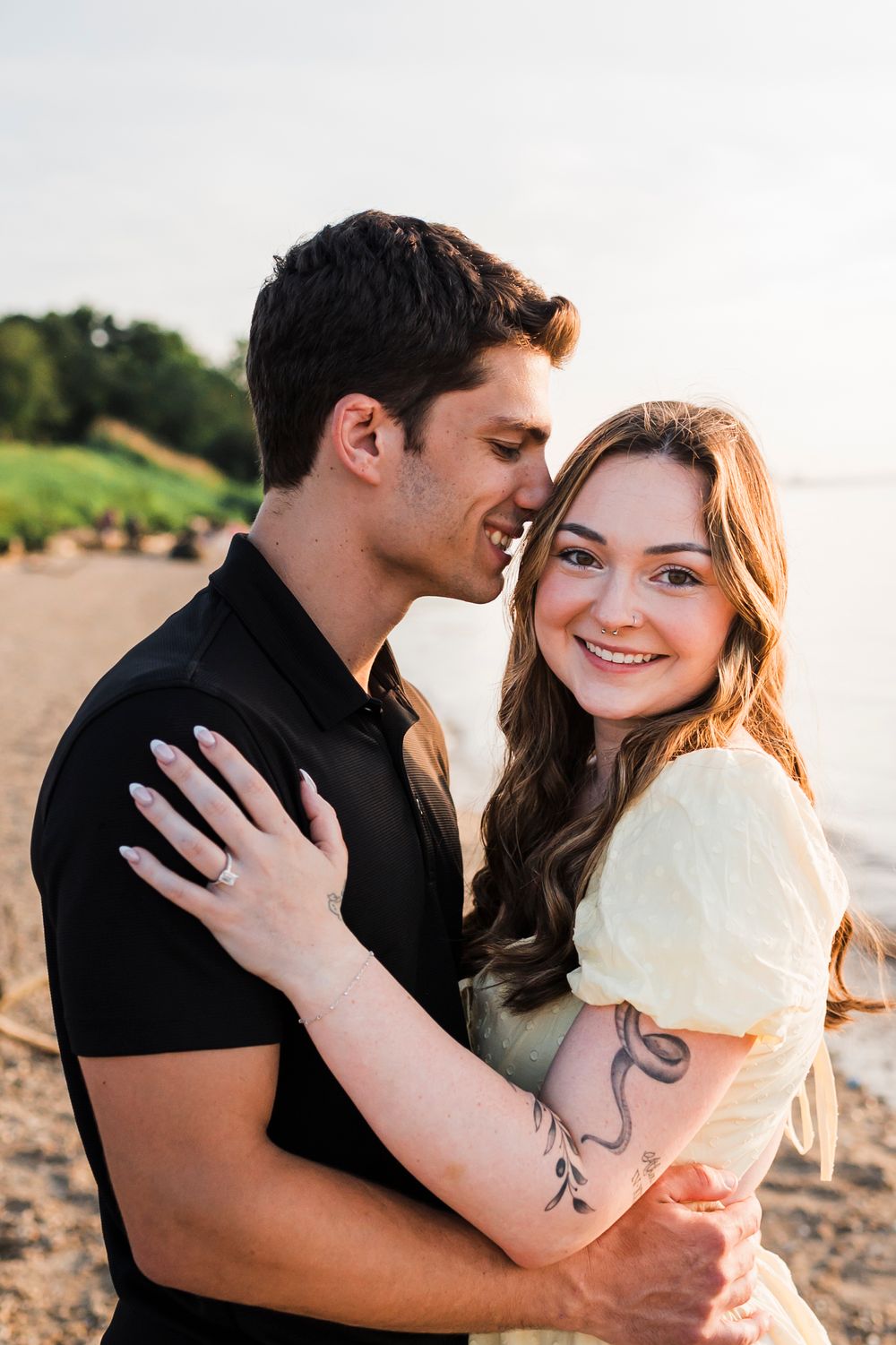 A romantic couple embraces on a beach at sunset while sharing a tender moment together.