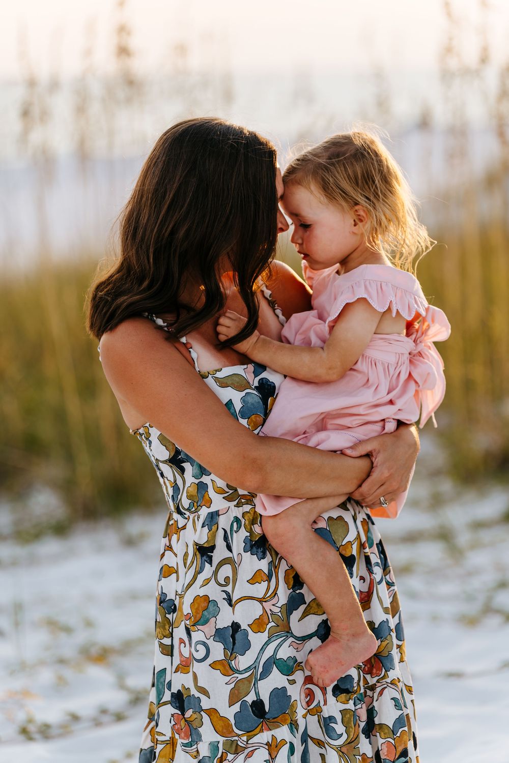 Series of tender moments between parent and child on sandy beach at sunset.