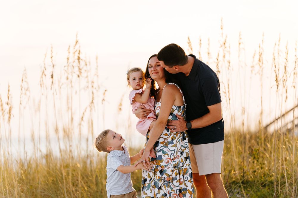 Candid family beach photos with parents and children playing in soft evening light.