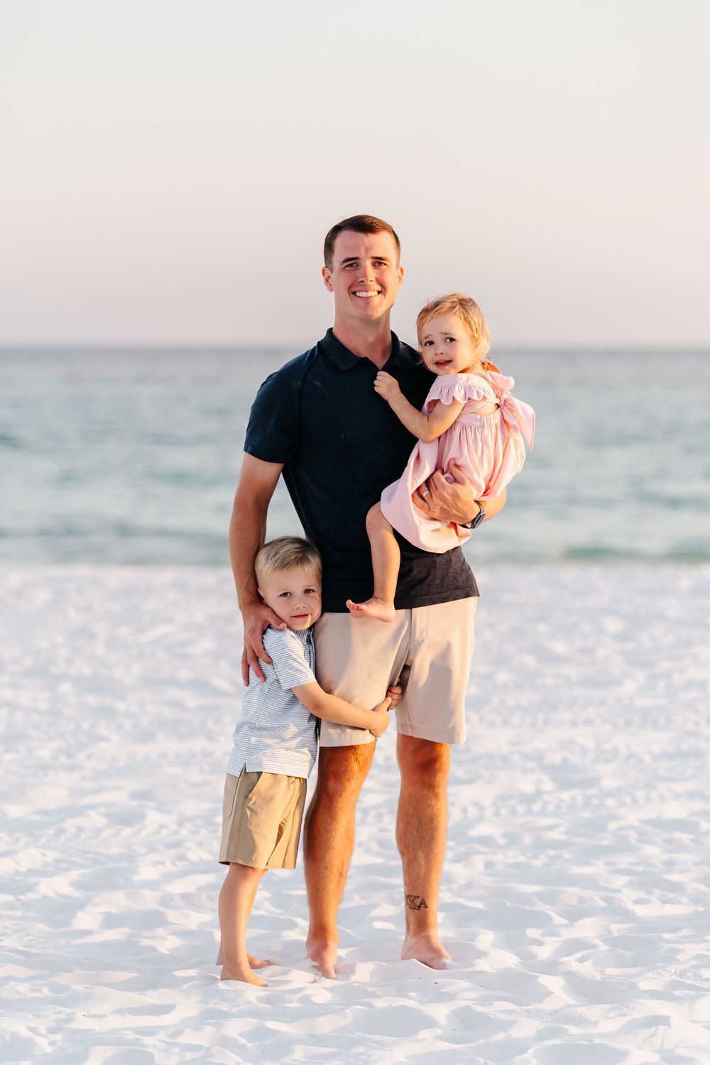 A parent and child share joyful moments together while walking on a white sandy beach at sunset.