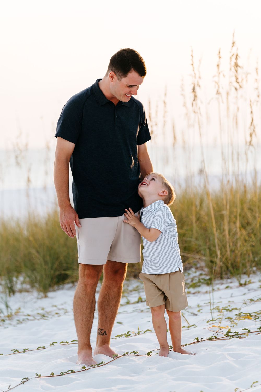 Family enjoying a tender moment together while walking on white sandy beach at sunset.