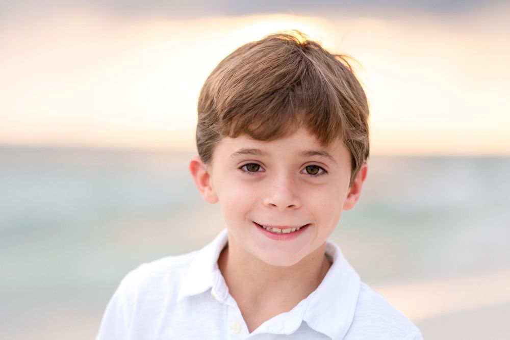 Candid portrait of someone wearing a white shirt against a soft sunset sky background.