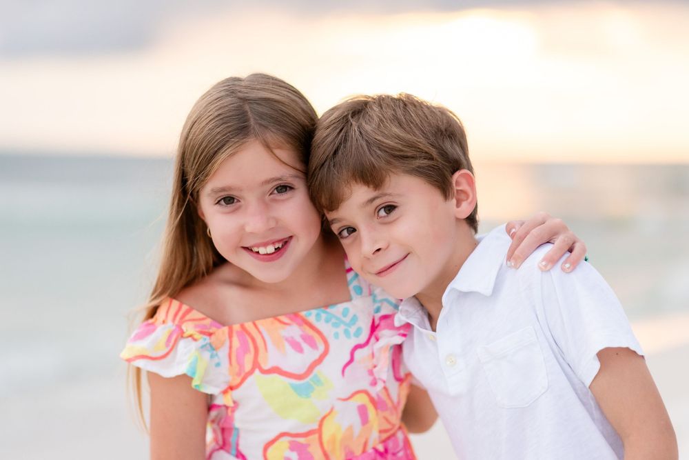 Family enjoying a sunset photoshoot together on a white sandy beach.
