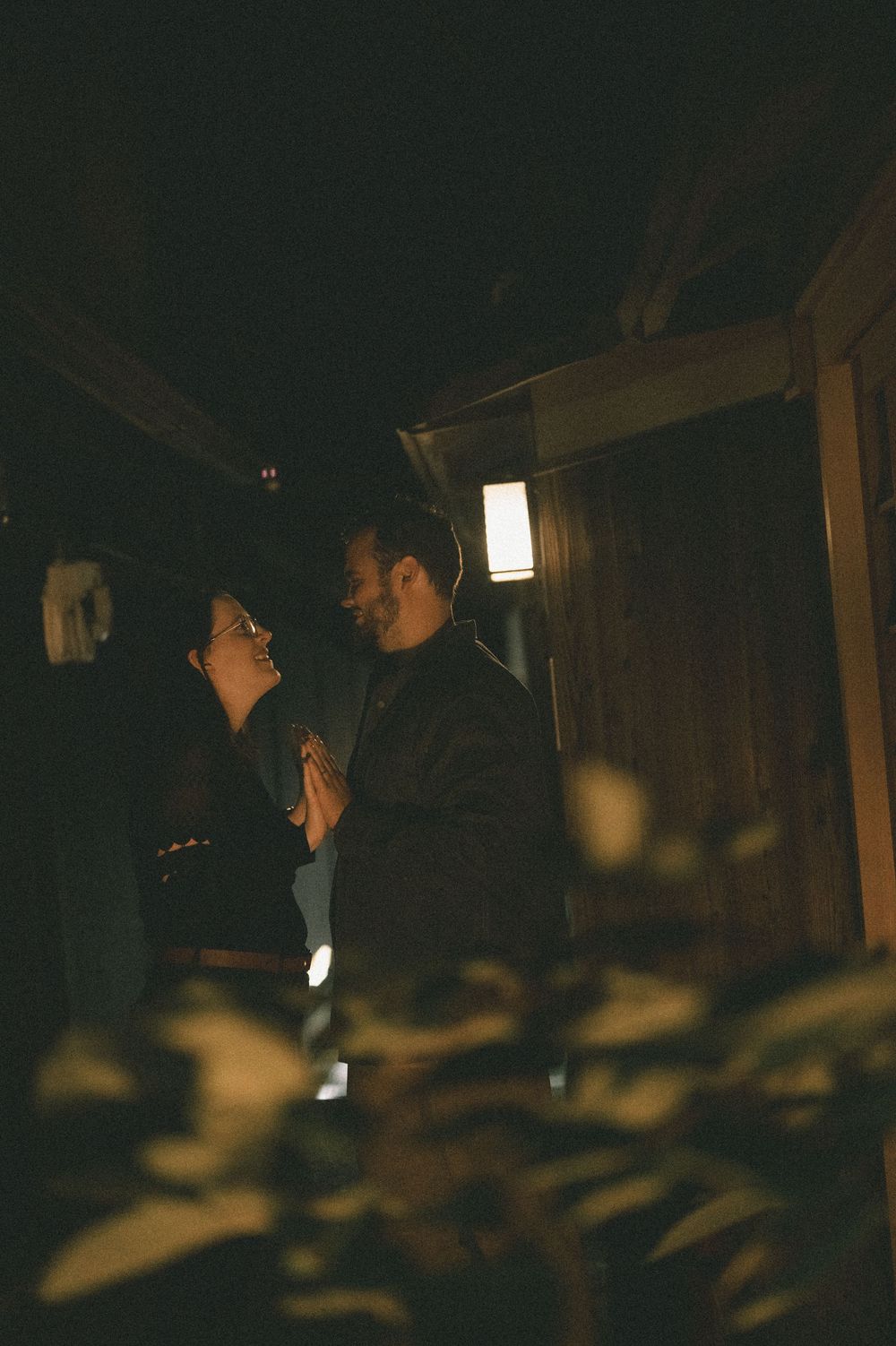 Romantic couple sharing a tender moment in a dimly lit Japanese garden at night.