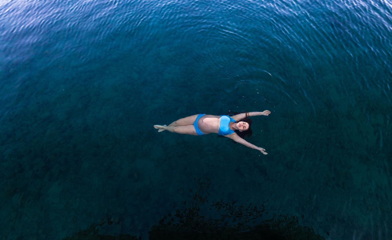 Aerial view of swimmers floating in deep blue ocean waters.