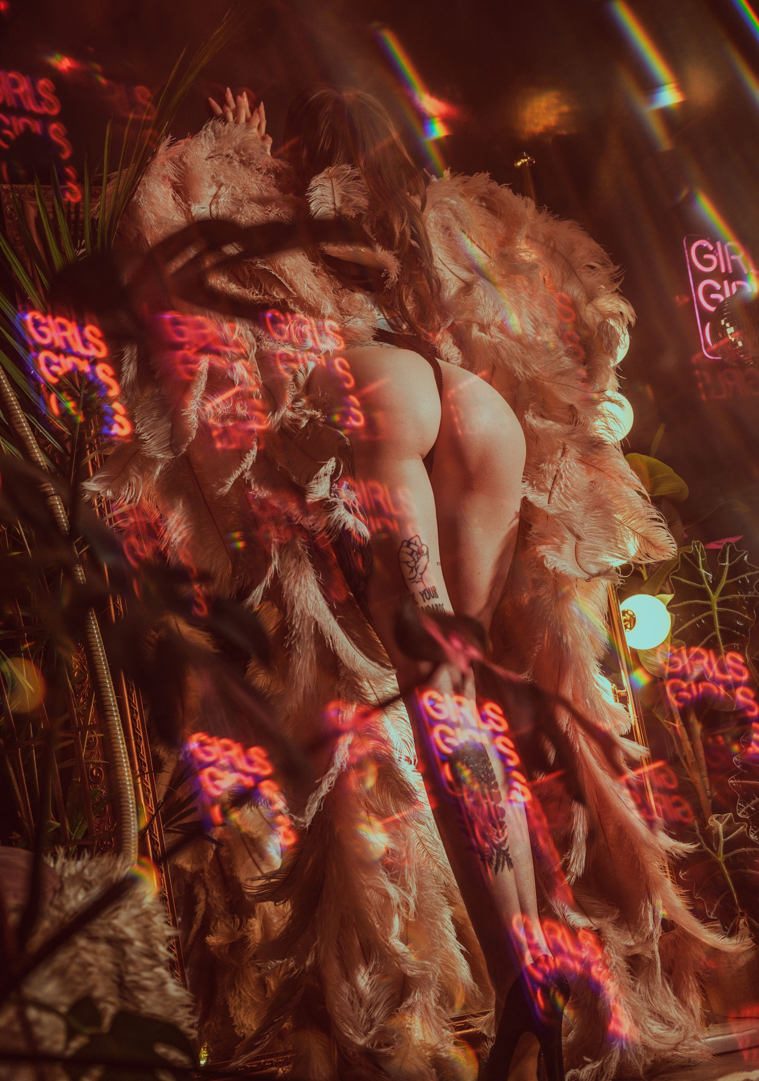 Performers in feathered costumes dance under red neon lights at a nightclub venue.
