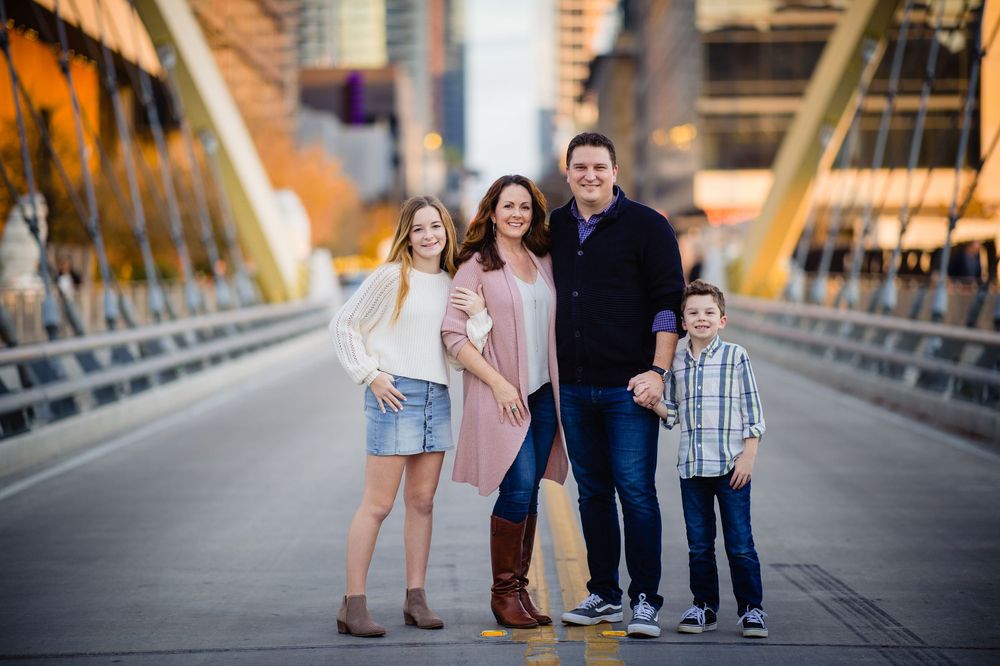 A happy family poses together on a bridge during a golden hour photo session.