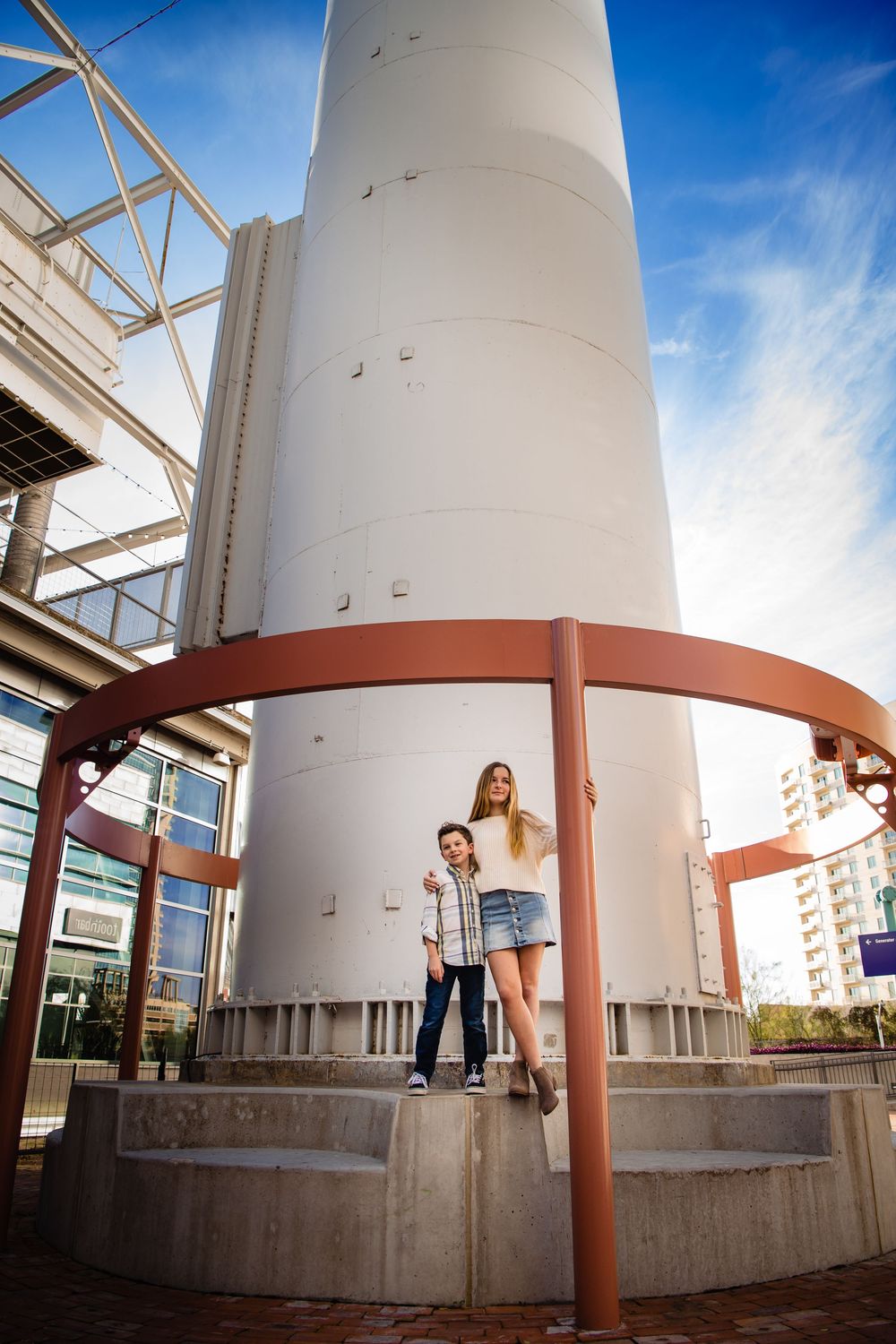 A series of architectural photos showing white cylindrical columns with orange metal supports against a bright blue sky.