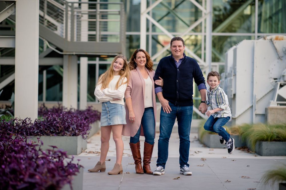 A collage of candid family photos taken outdoors with modern urban architecture and purple flowers in the background.