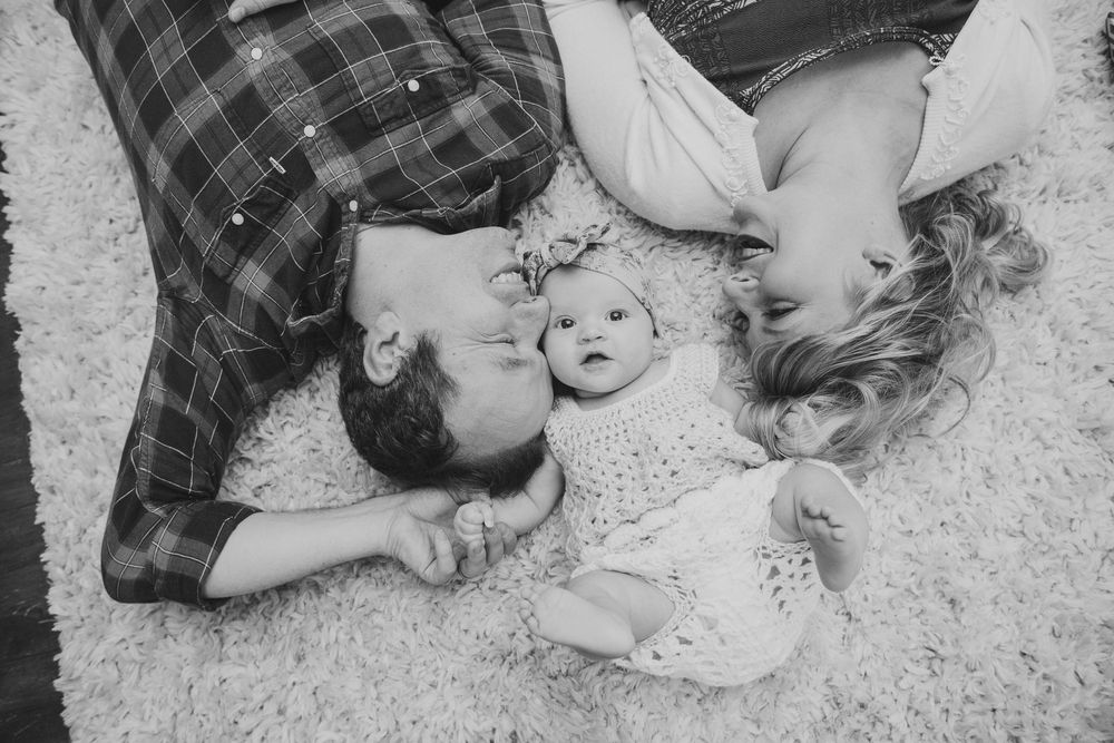 A collage of black and white photos showing a couple lying on a carpet in various playful and romantic poses.