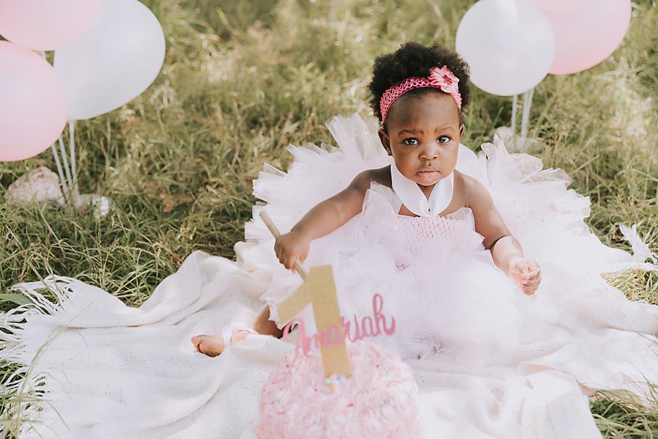 Outdoor birthday celebration setup with pink and white decorations on grass.