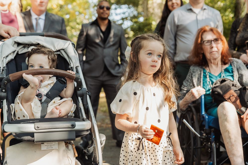 A diverse group of people gather outdoors for a social event on a sunny autumn day.