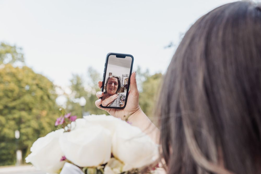 A couple takes selfies together during their wedding day outside a historic building.