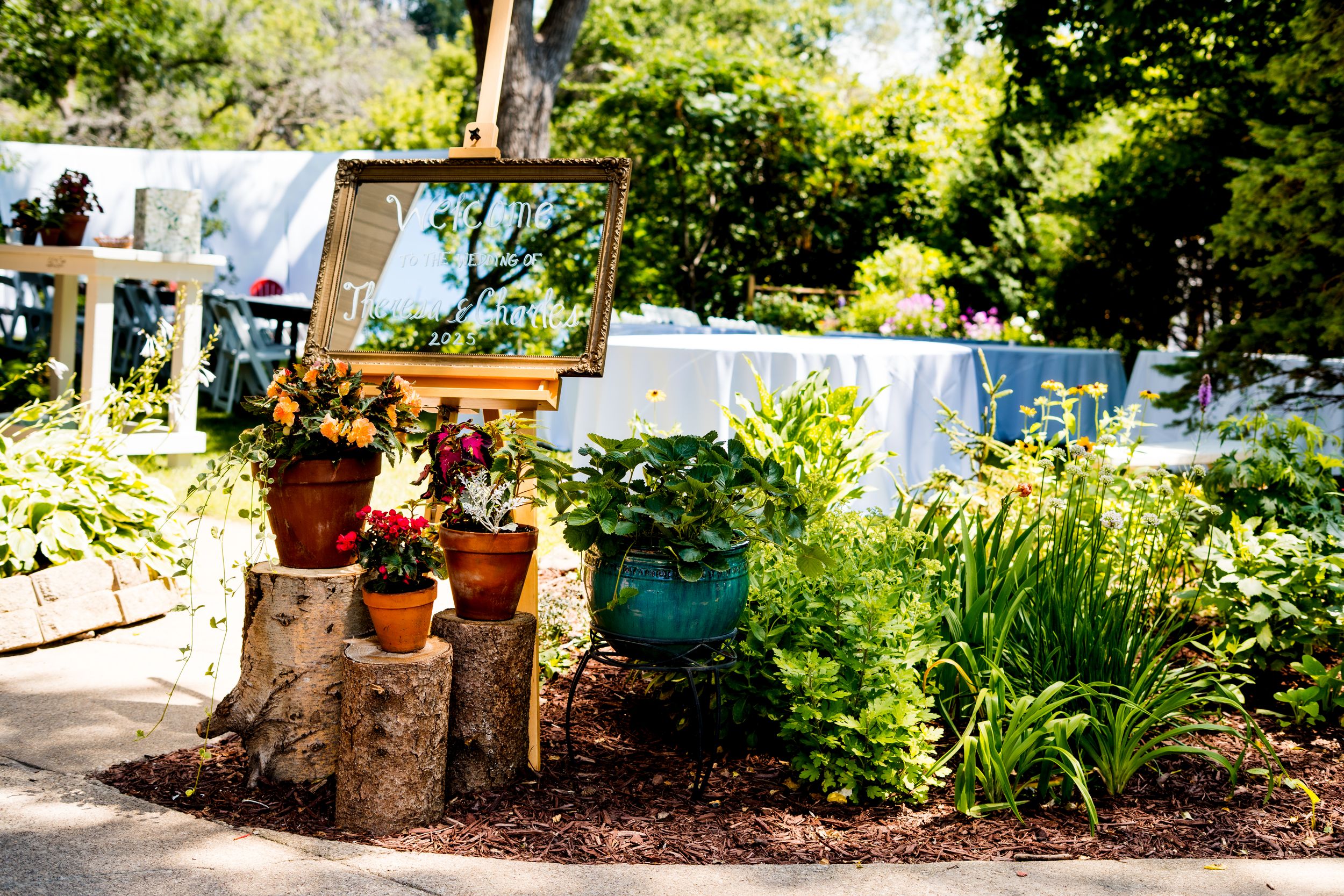 A stone garden path with decorative potted plants and landscaping leads through a lush green backyard.
