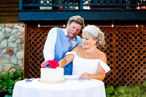 Wedding reception celebration under a wooden pergola decorated with string lights and floral arrangements.