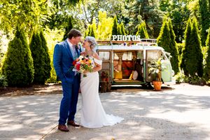 A couple shares a tender moment during their outdoor garden wedding ceremony surrounded by lush greenery and trees.