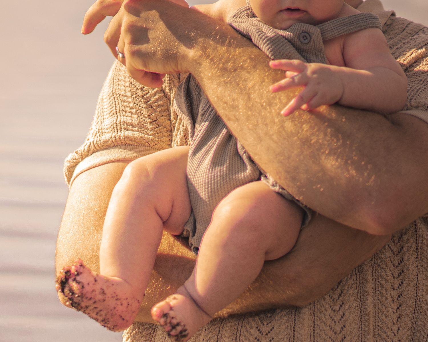 Gentle hands holding small feet against warm sunset lighting.
