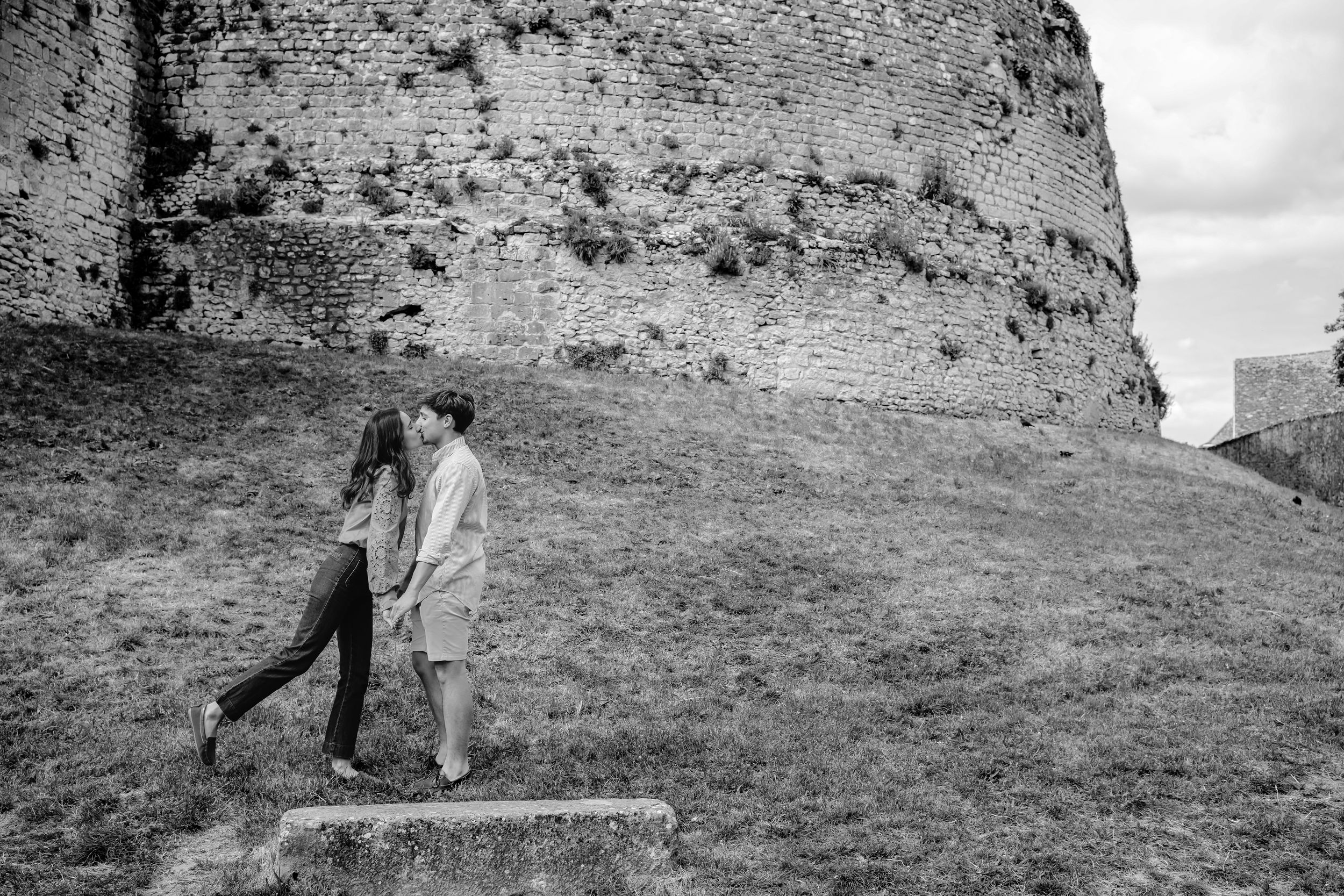 A couple explores a historic stone wall setting in dramatic black and white photography.