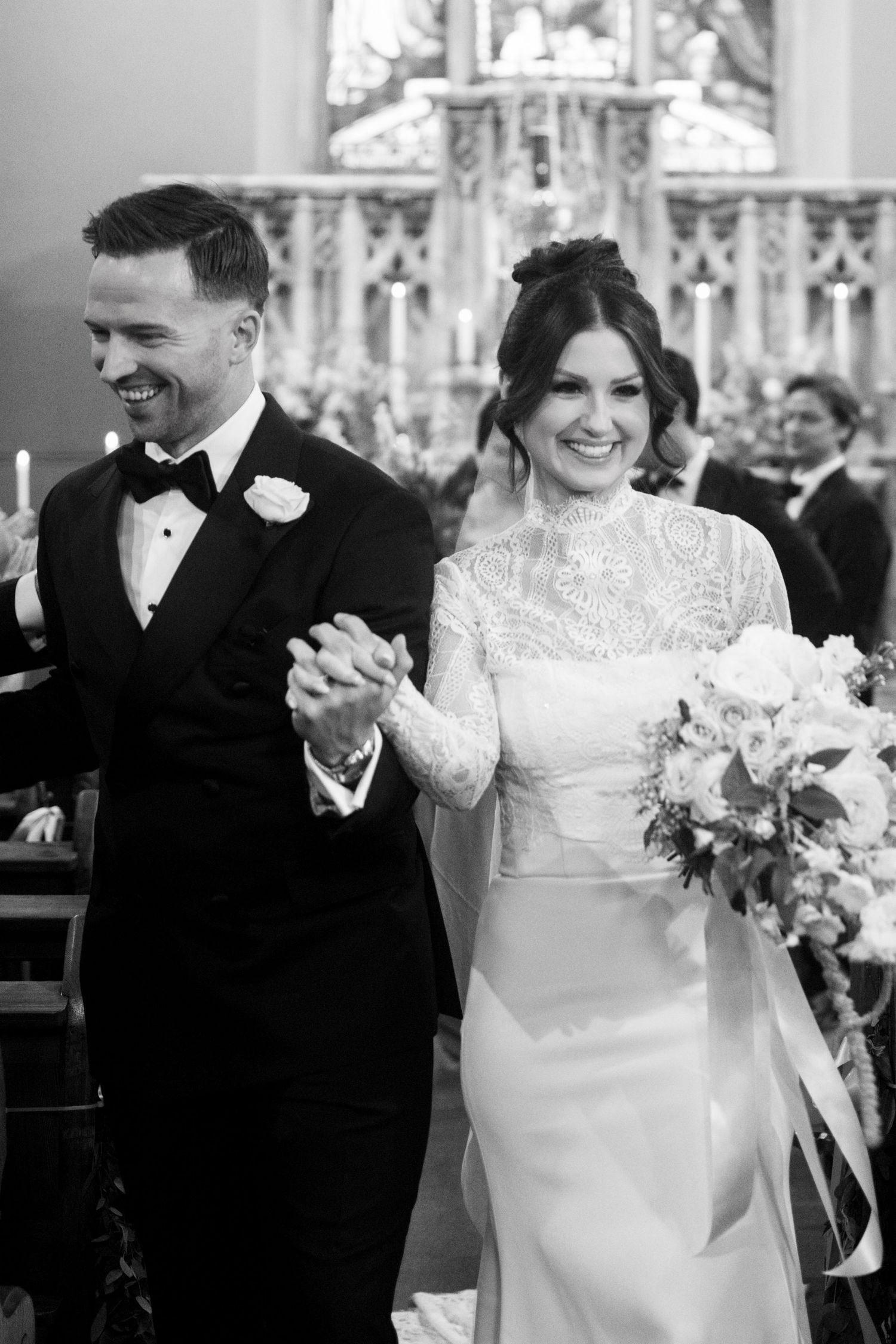 A classic black and white wedding party photo on grand stone steps of an ivy-covered castle.