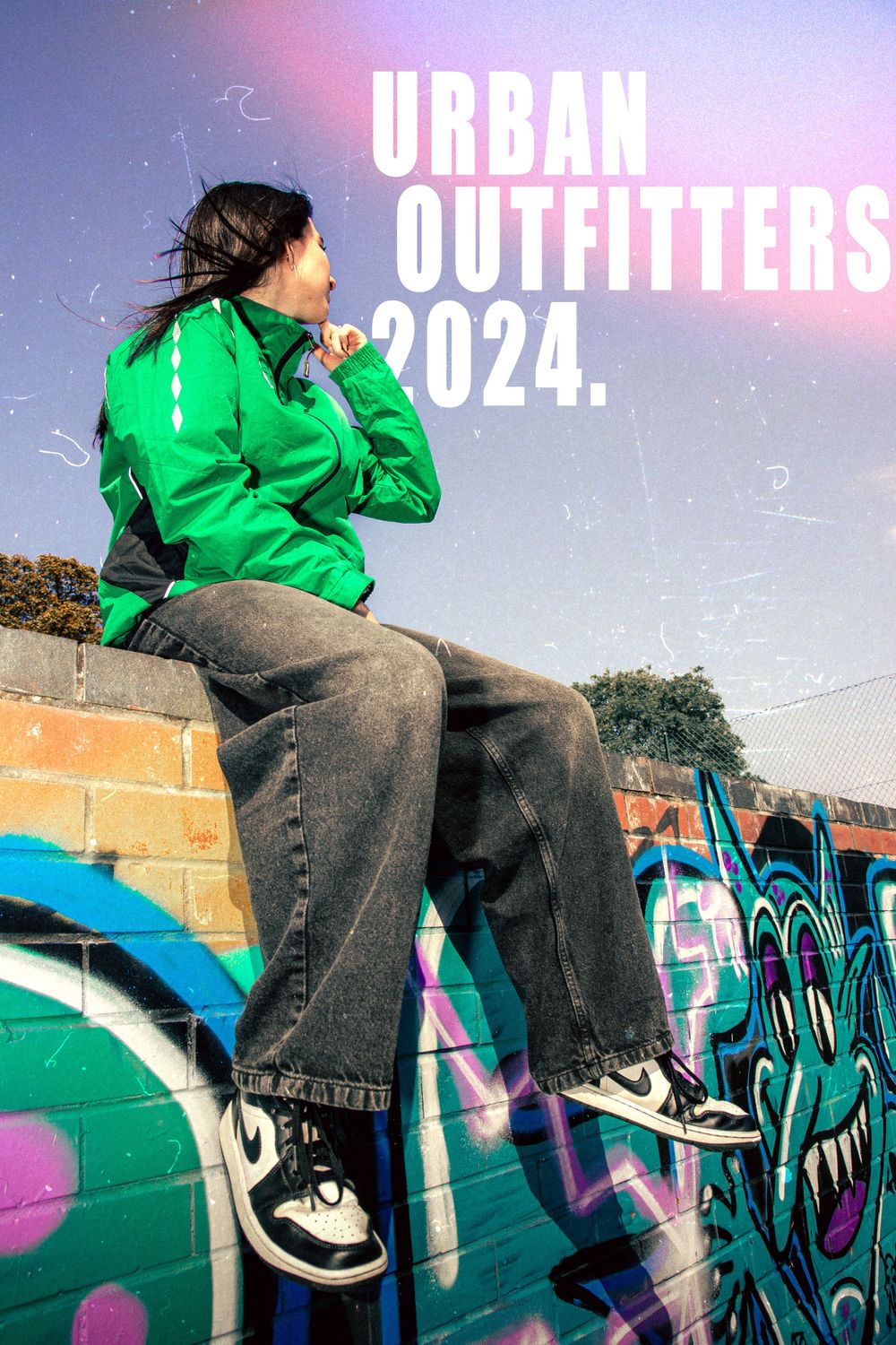 Urban street style photography with green jacket against graffiti wall featuring 'Urban Outfitters 2024' text overlay.