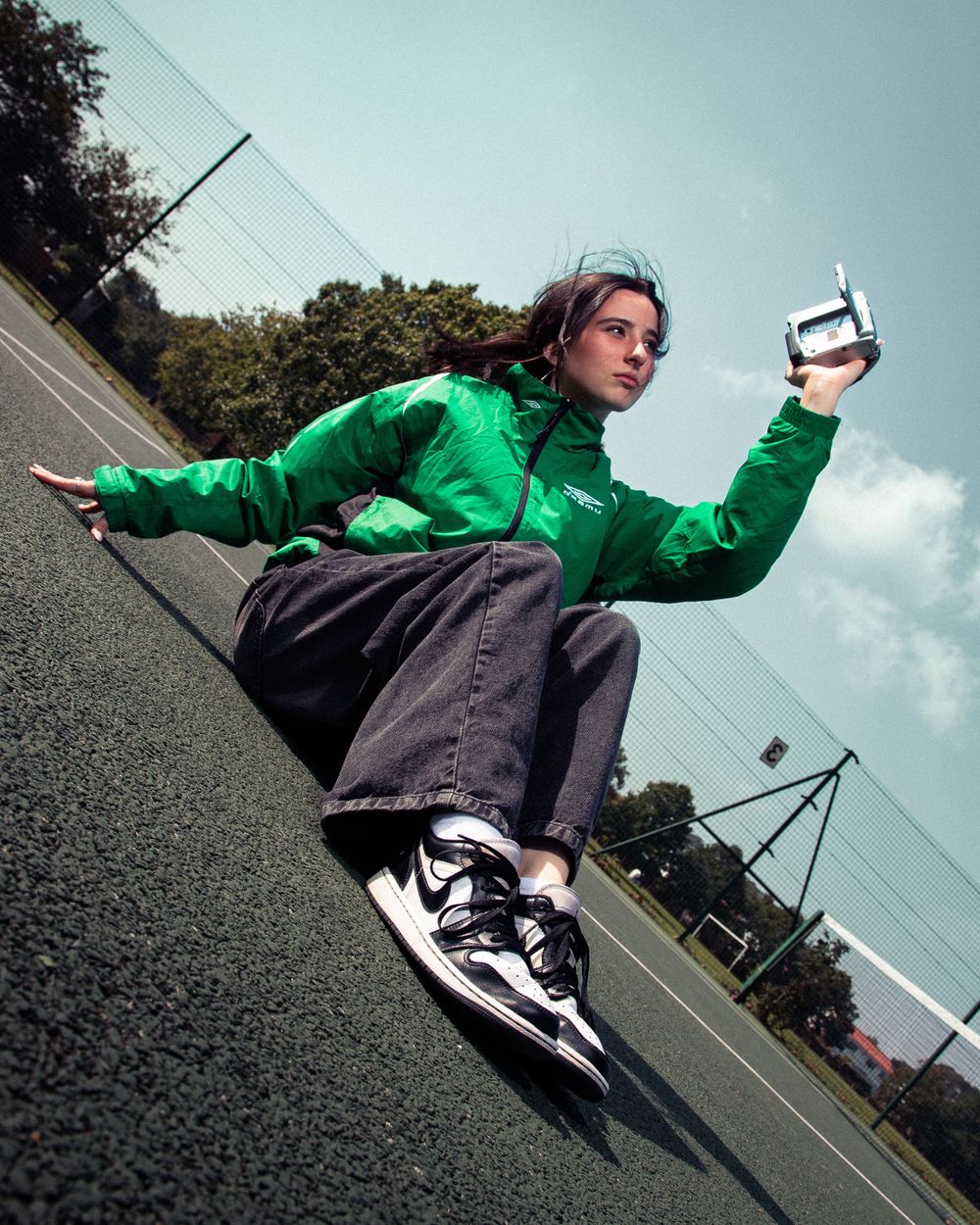 Dynamic shot of someone in a bright green jacket performing a creative pose on asphalt ground.