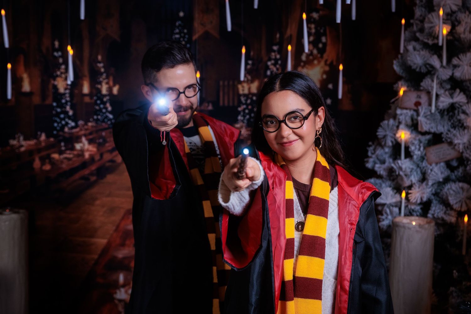 Person wearing a red and yellow striped scarf poses near decorated Christmas trees with twinkling lights.