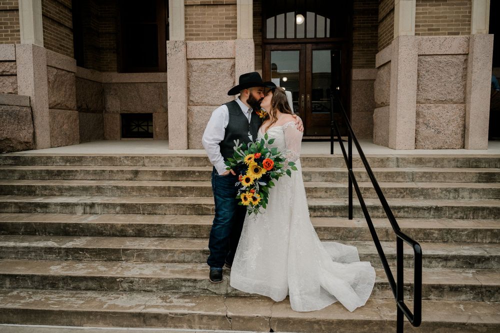 A wedding couple shares an intimate moment on historic stone steps with sunflowers.