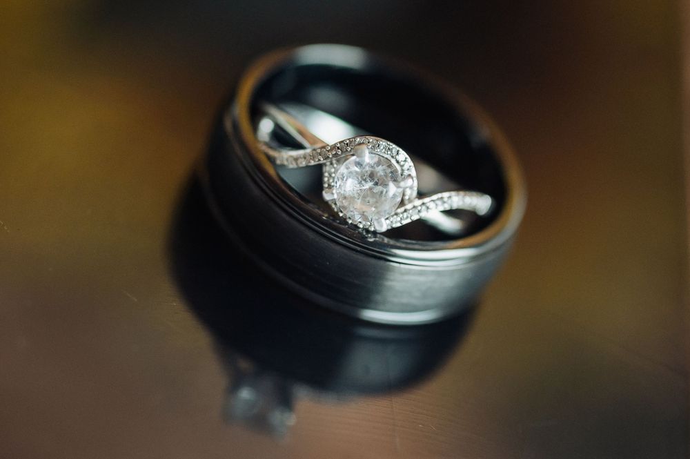 A stunning diamond engagement ring photographed on a black lens case with artistic bokeh.