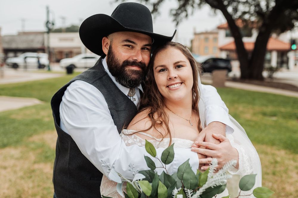 A western-style wedding portrait featuring greenery and casual outdoor setting.