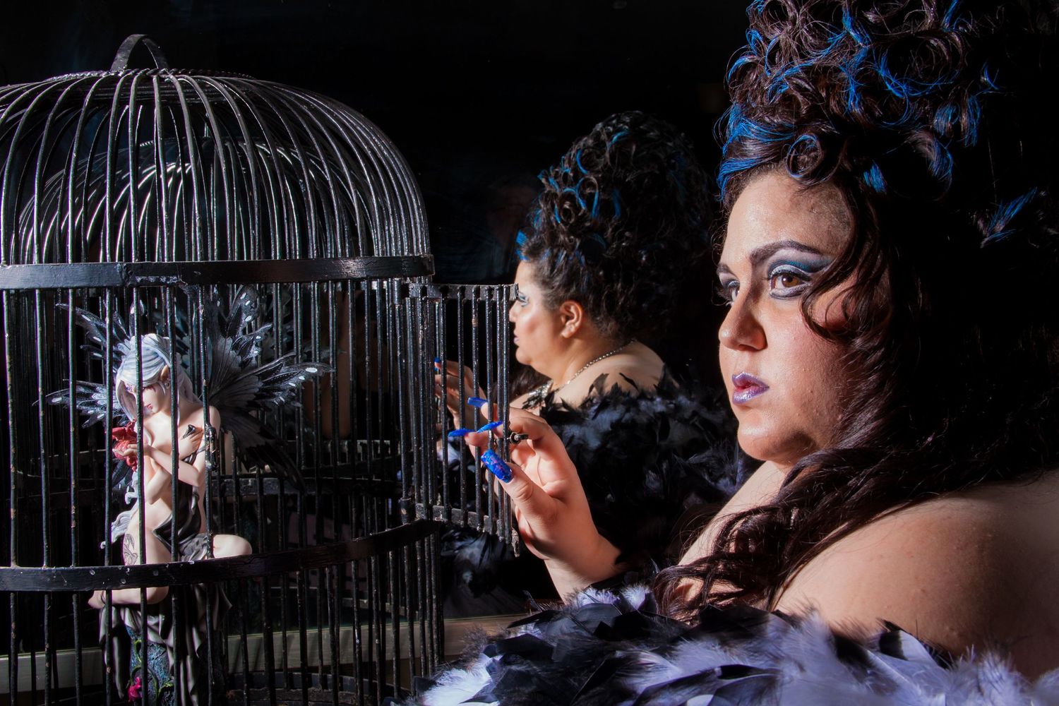 An artistic dark portrait featuring a decorative birdcage and dramatic lighting with gothic-inspired styling and feather accents.