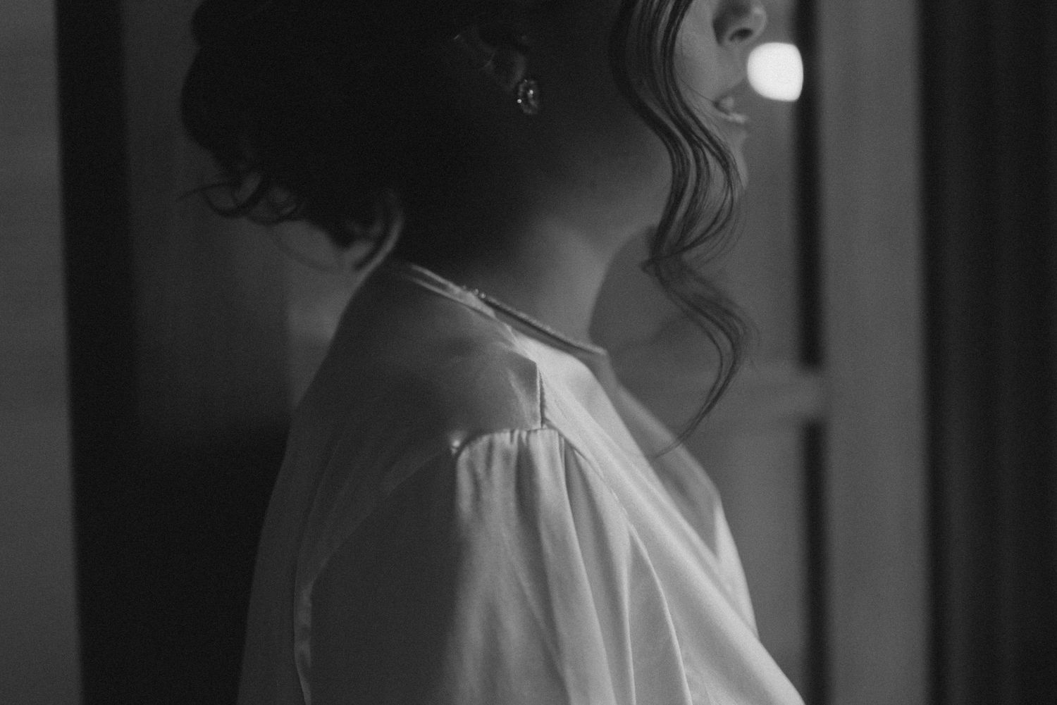 Side profile of a person in a white robe gazing upward in moody black and white lighting.