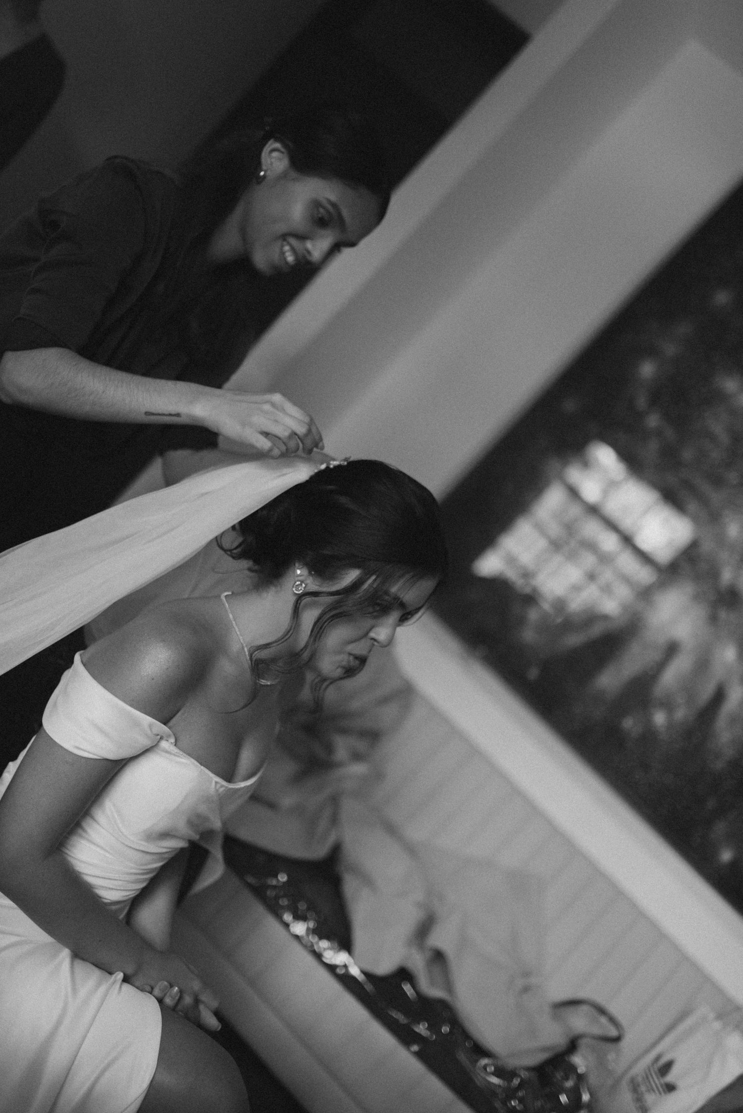 Black and white image of getting dressed preparation with one person helping another.